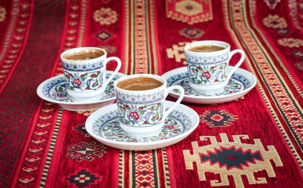 Drei traditionelle bosnische Kaffeetassen (Fildžan) mit frisch gebrühtem Kaffee auf einem roten, gemusterten Ćilim